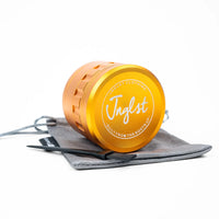 An orange metallic grinder with a gray drawstring pouch and black tool, branded 'Jnglst', on a white background.