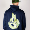 Person wearing a navy hoodie with a green Junglist flame design on the back against a plain background