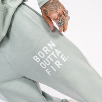 Aloe green streetwear joggers close up of Born Outta Fire screen print detail