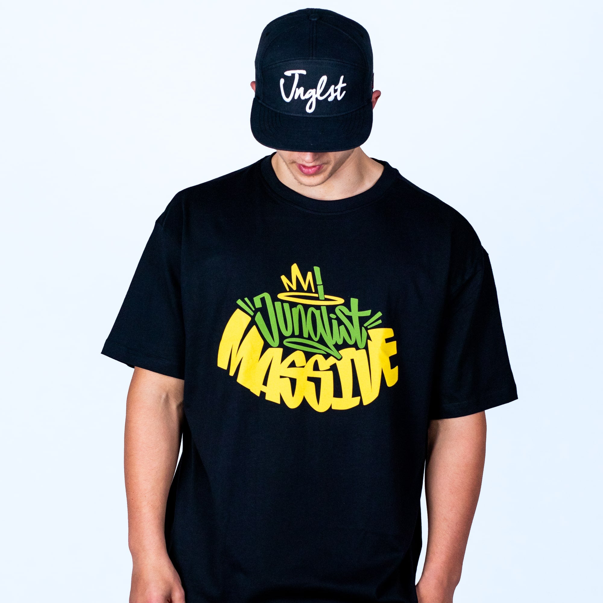 Person wearing a black t-shirt with colorful text and a black cap with 'Jnglst' on a light gray background