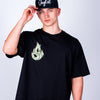 Person wearing a black Born Outta Fire t-shirt with a green logo and a black cap on a light gray background