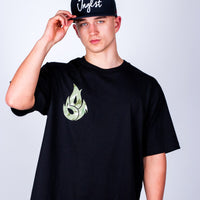 Person wearing a black Born Outta Fire t-shirt with a green logo and a black cap on a light gray background