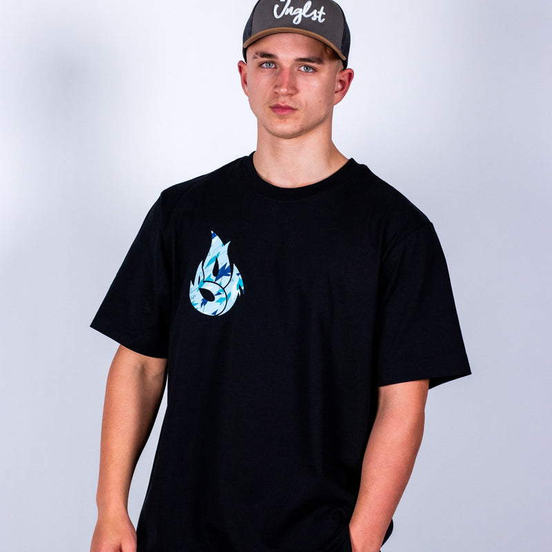 Person wearing a black Junglist t-shirt with a blue graphic design and a cap on a light gray background