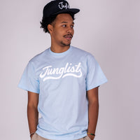 Man wearing a light blue 'Junglist' t-shirt and black cap on a plain background