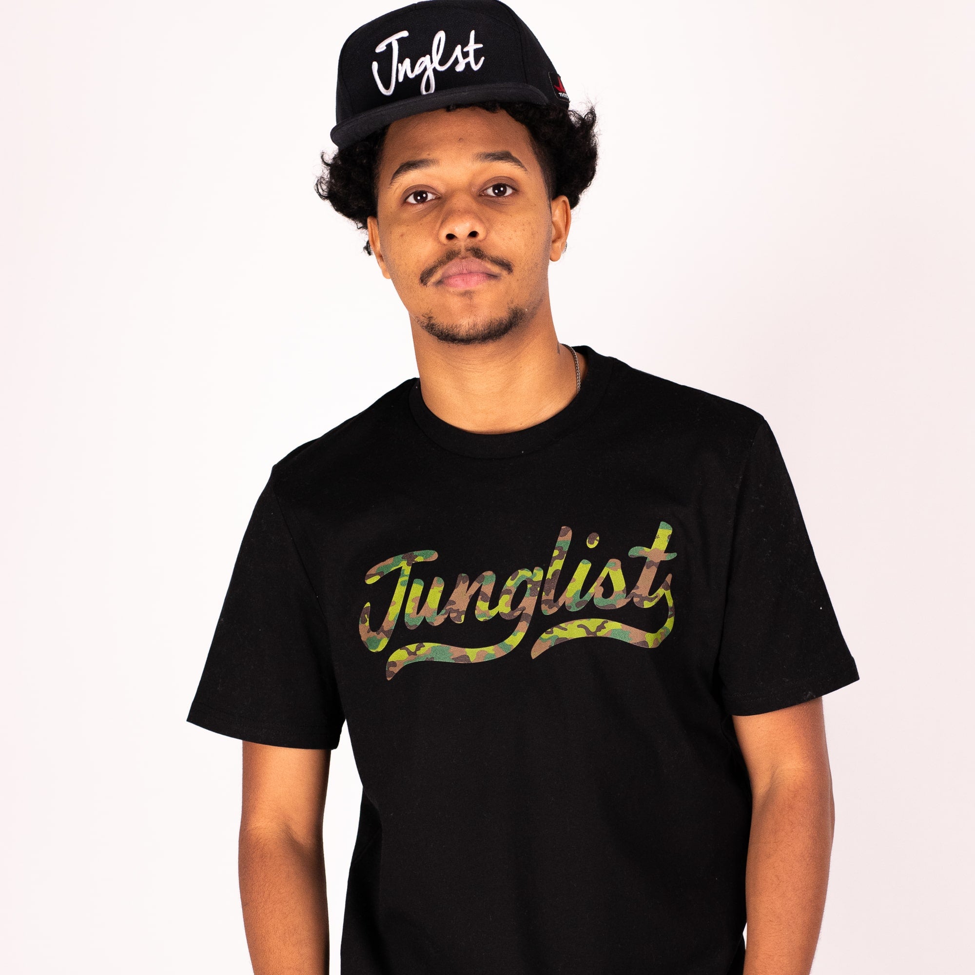 Person wearing a black 'Junglist' t-shirt and cap on a white background