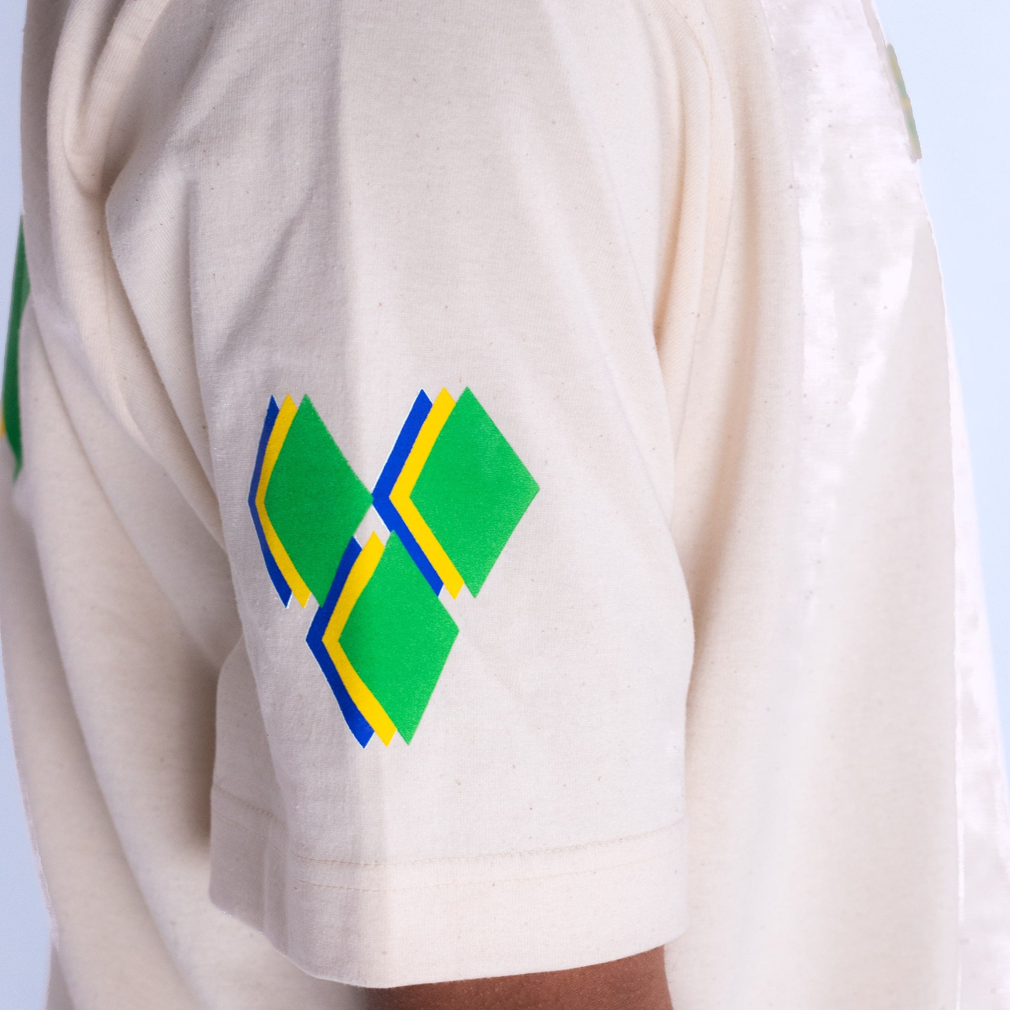 White yardrock t shirt with green and blue geometric pattern on a light blue background