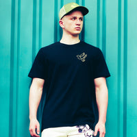 Man wearing a black t-shirt with a white dove design against a teal background