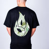 Person wearing a black junglist t-shirt with a green flame design on the back against a plain background