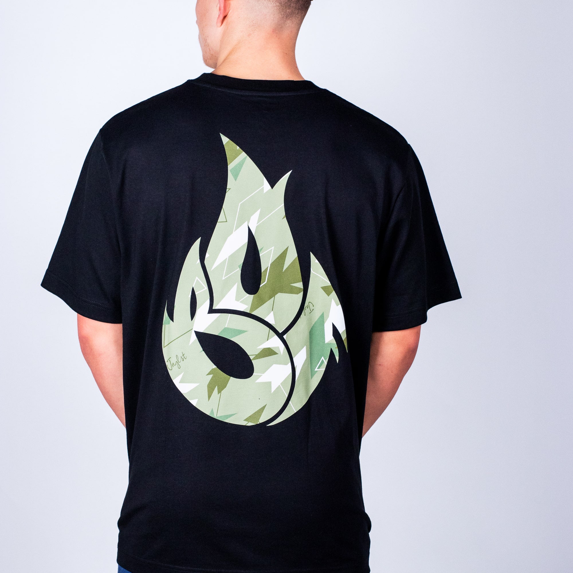 Person wearing a black junglist t-shirt with a green flame design on the back against a plain background