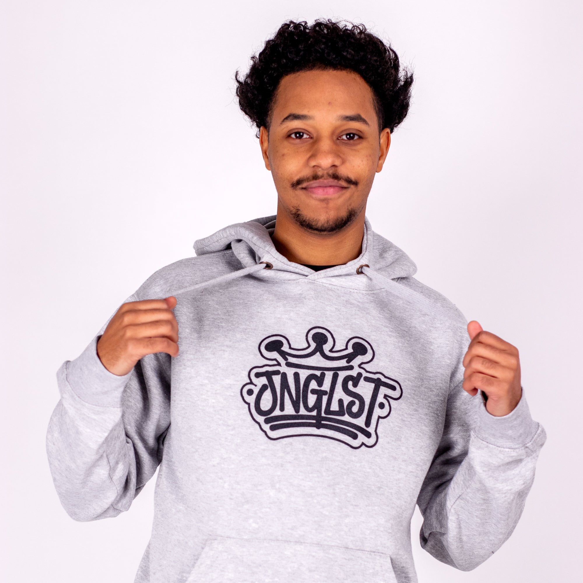 Person wearing a gray hoodie with 'JNGLST' logo on a white background