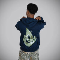 A Junglist viewed from behind wearing a navy blue hoodie with a large green camouflage graphic on the back, paired with camouflage pants, against a plain gray studio background.