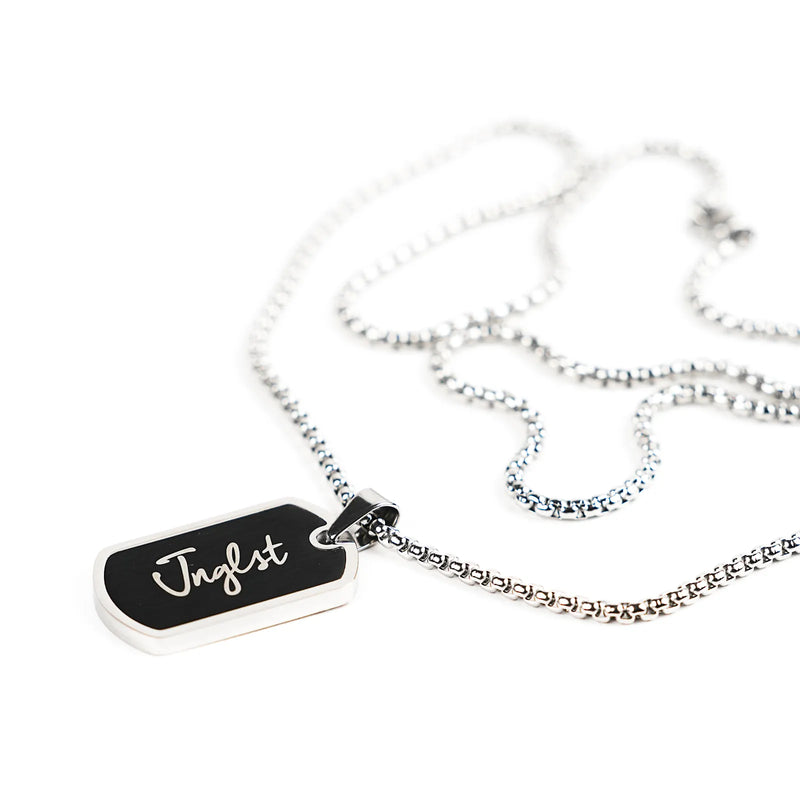 A silver-toned chain necklace with a rectangular black pendant engraved with the name 'Jnglst' in white script, shown on a clean white background.