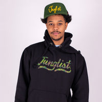 Person wearing a black hoodie and green cap with 'Junglist' branding on a white background
