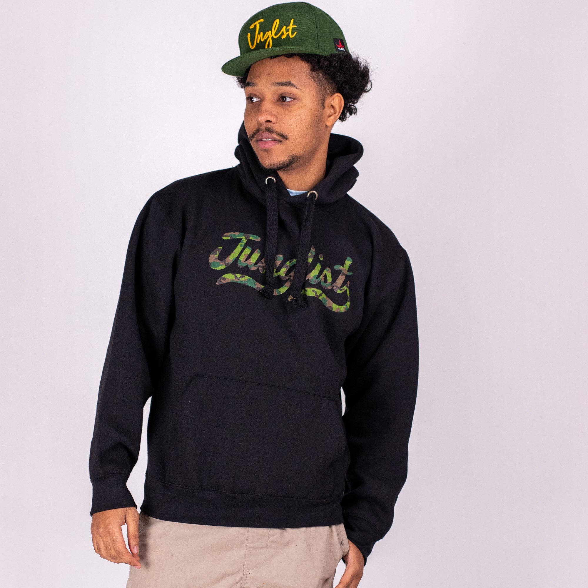 Person wearing a black hoodie and green cap with 'Justist' branding on a white background