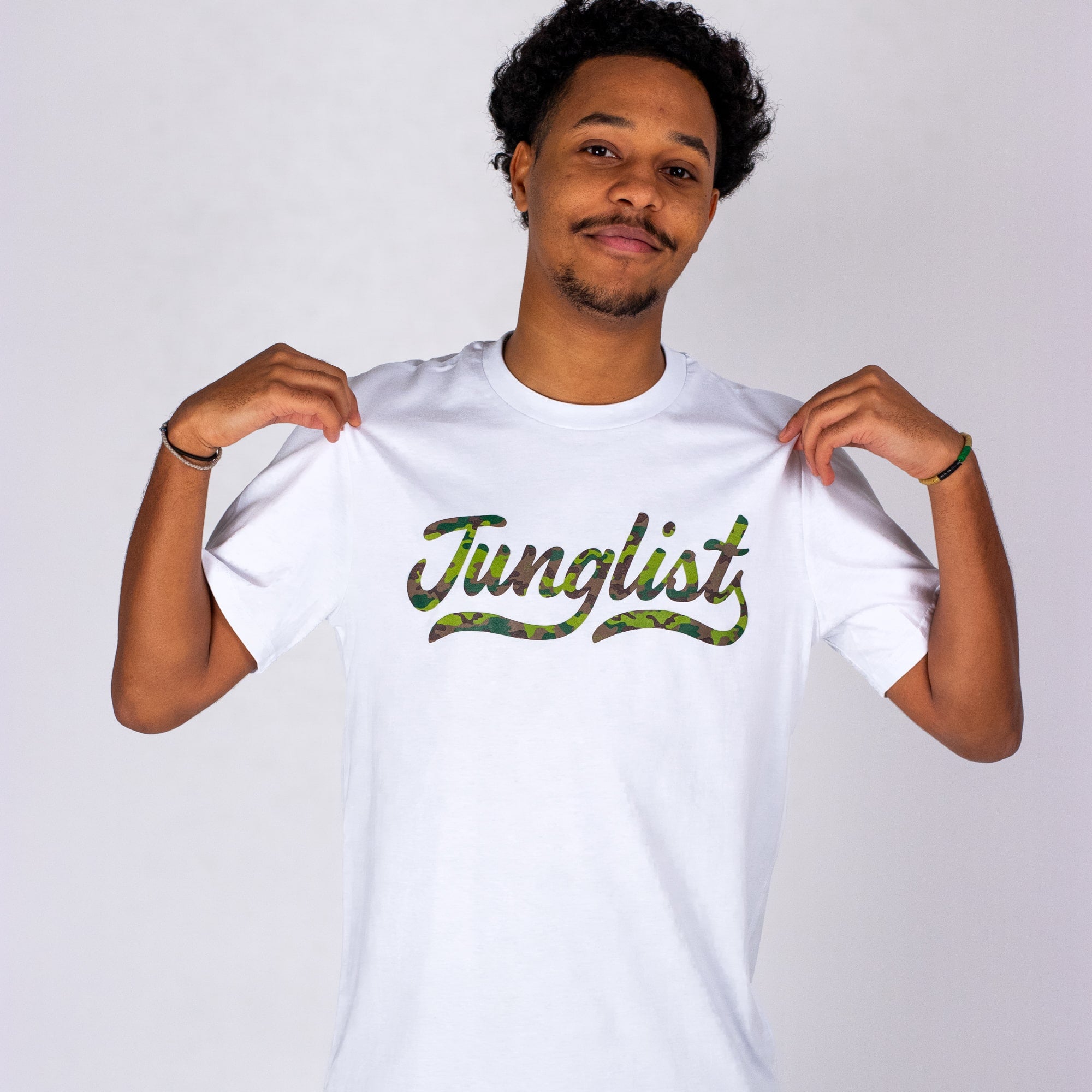 Person wearing a white t-shirt with 'Junglist' printed on it against a plain background
