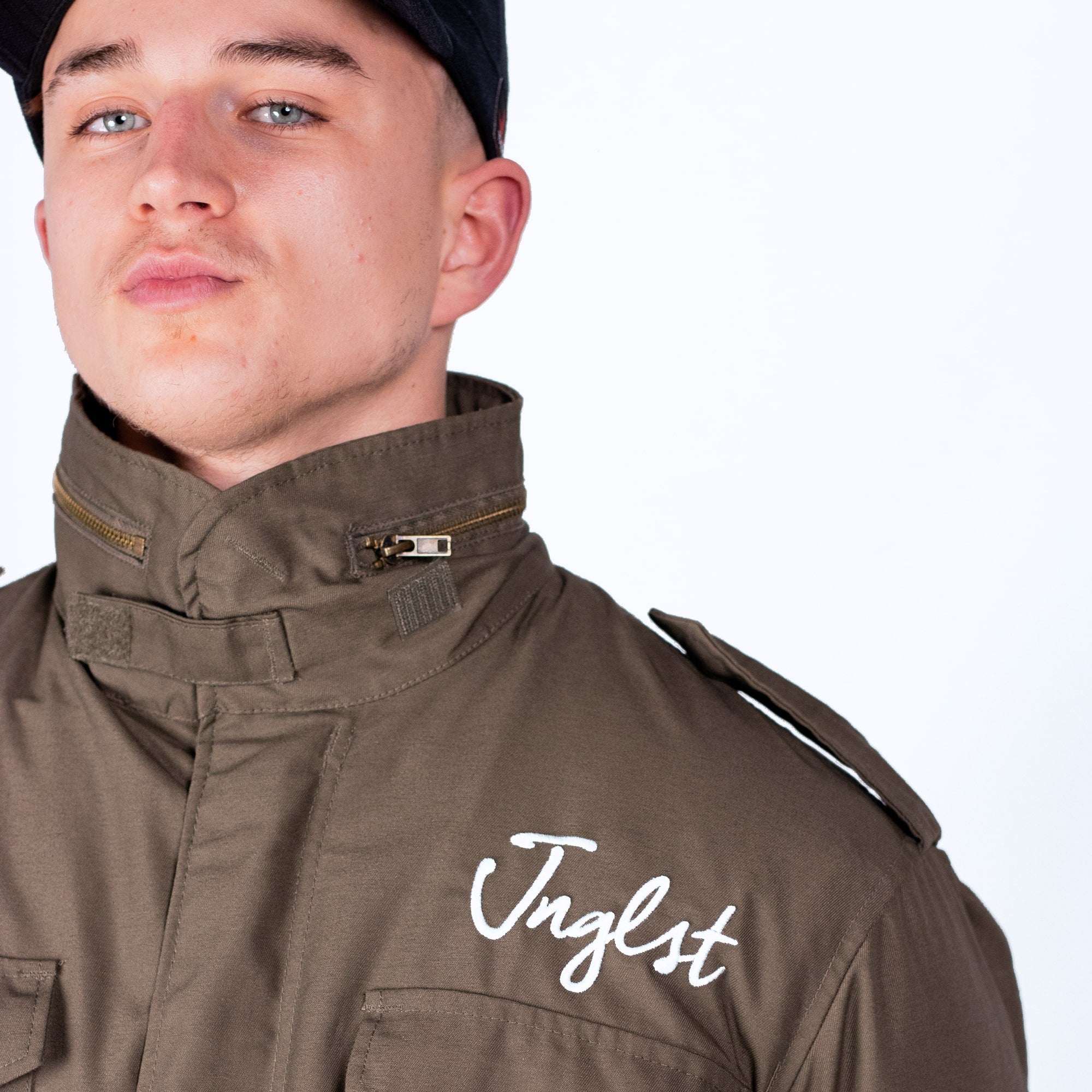 Person wearing a brown jacket with 'Jnglst' branding on a white background