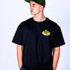 Person wearing a black t-shirt with yellow Junglist Massive text and a green cap on a white background