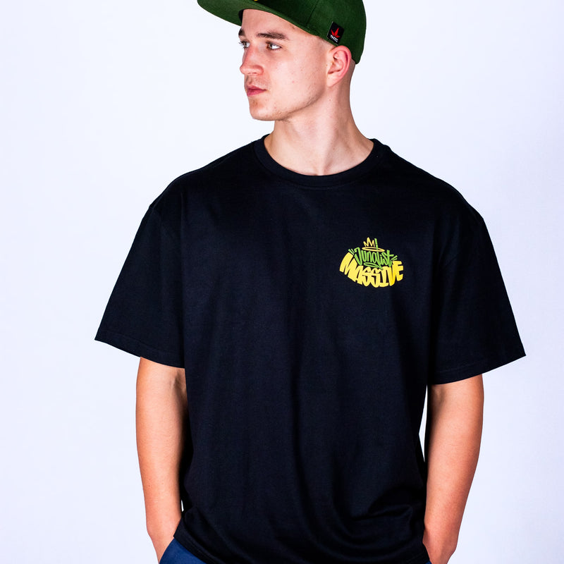 Person wearing a black t-shirt with yellow Junglist Massive text and a green cap on a white background