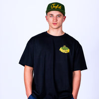 Person wearing a black t-shirt with yellow text and a green cap with yellow text on a white background