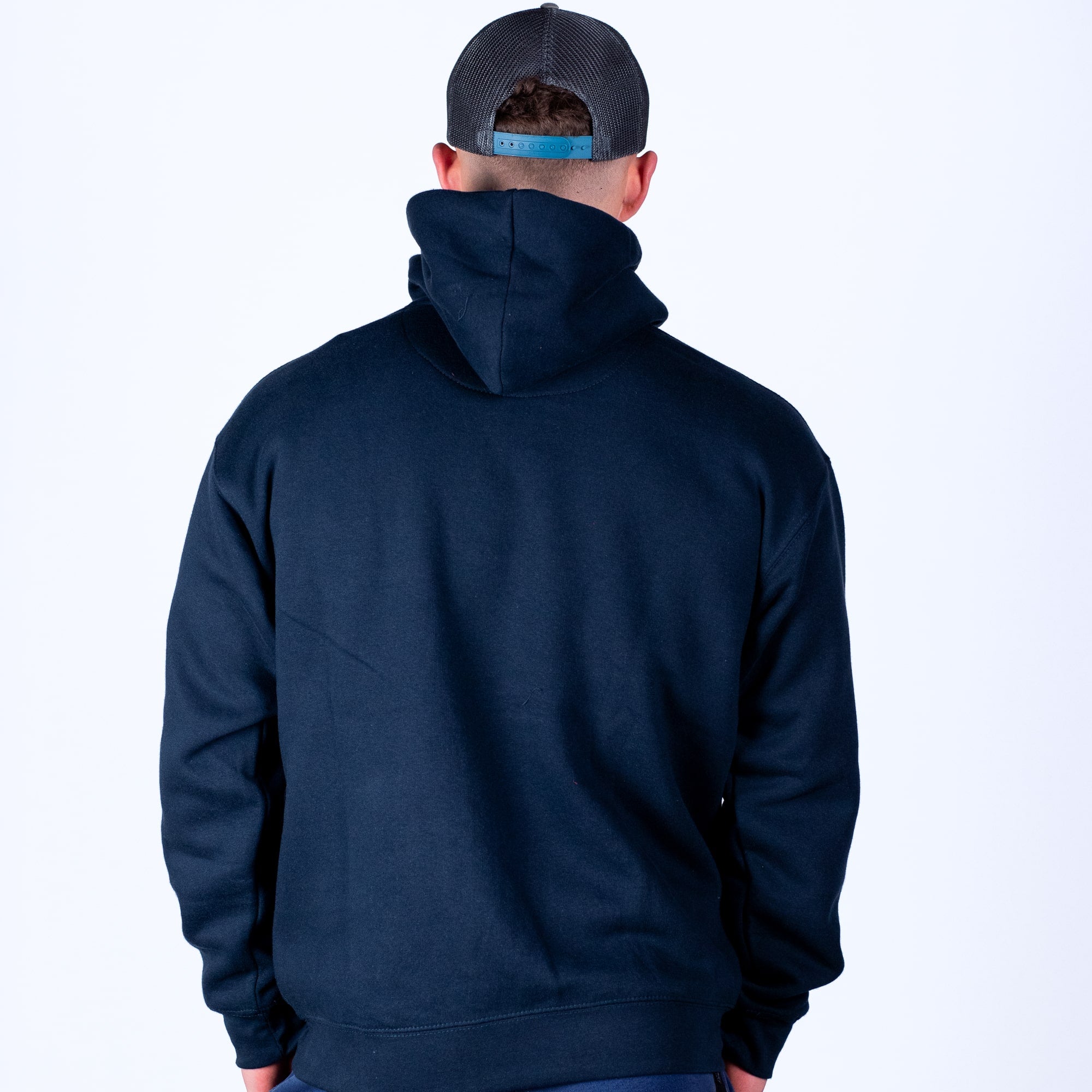Person wearing a navy blue hoodie and cap on a white background