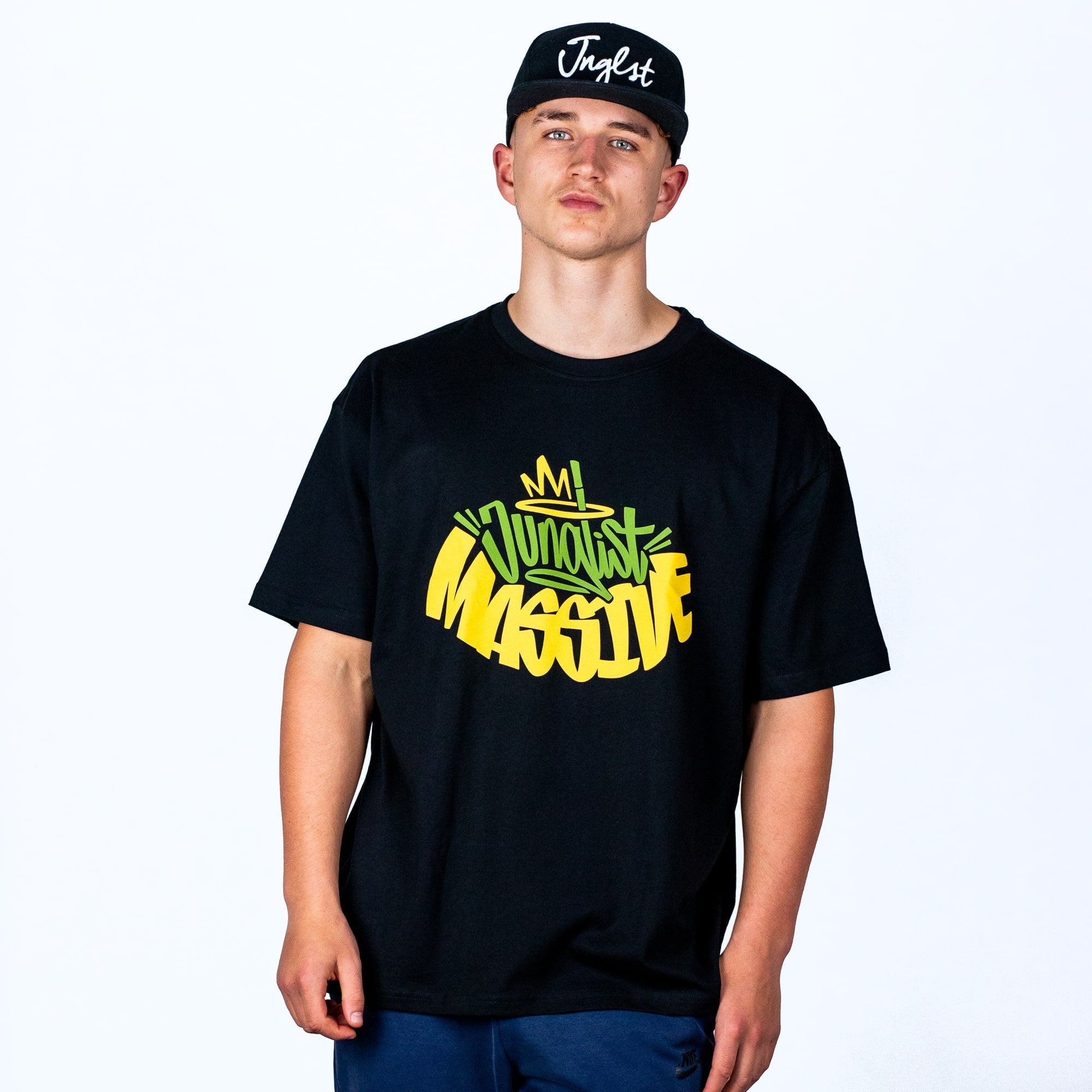 Person wearing a black oversized Junglist t-shirt with colorful text and a black cap on a white background