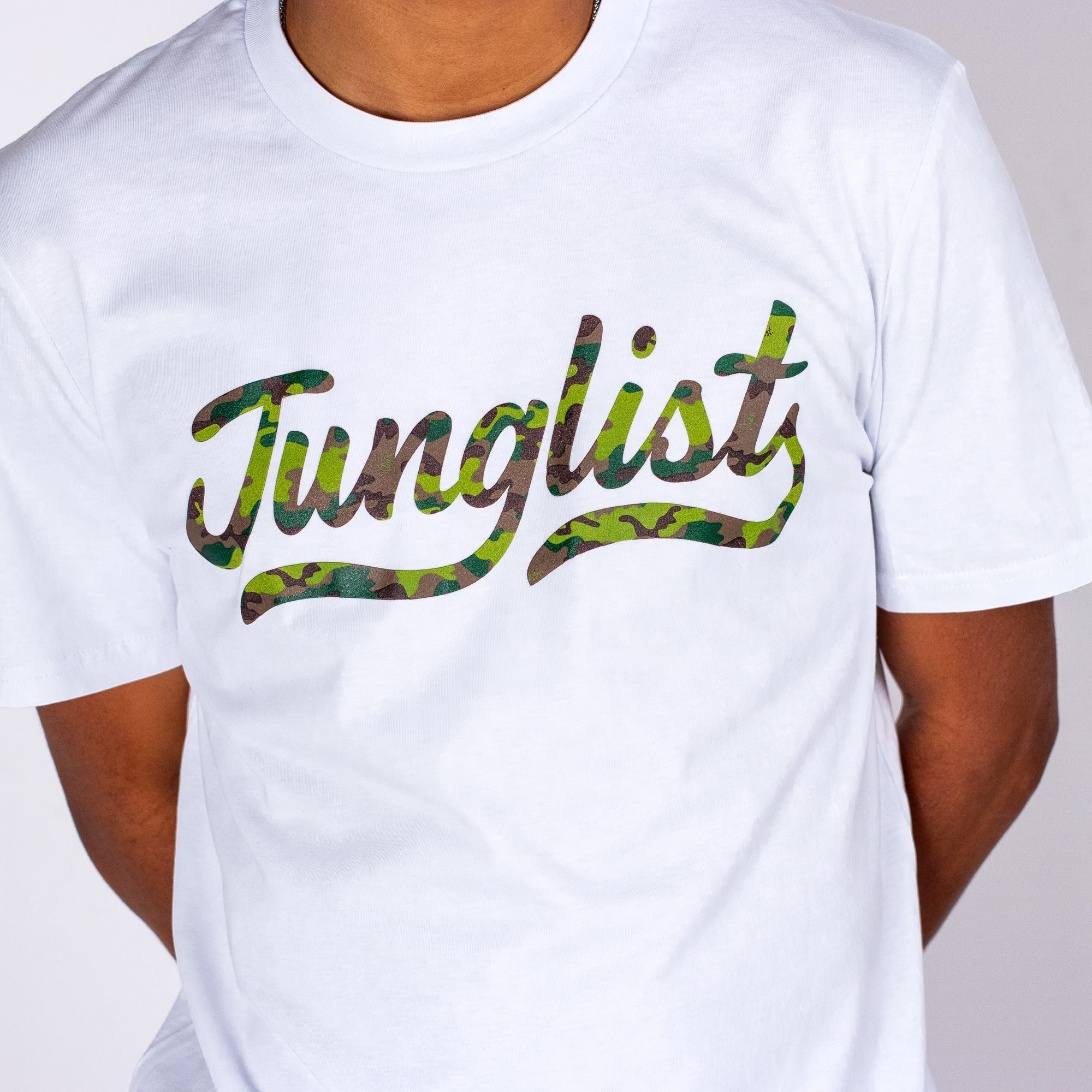 White t-shirt with 'Junglist' in camouflage print worn by a person