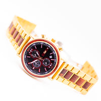 Bronze wristwatch with a red and black face on a white background