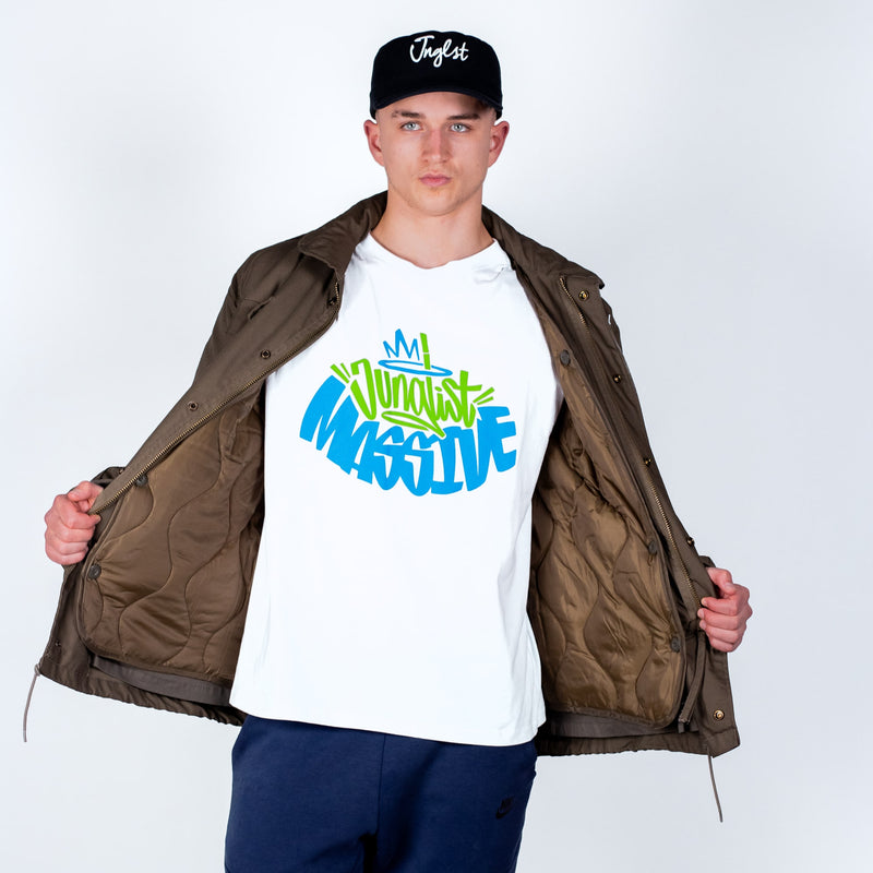 Person wearing a white t-shirt with colorful text, brown jacket, and black cap on a light gray background