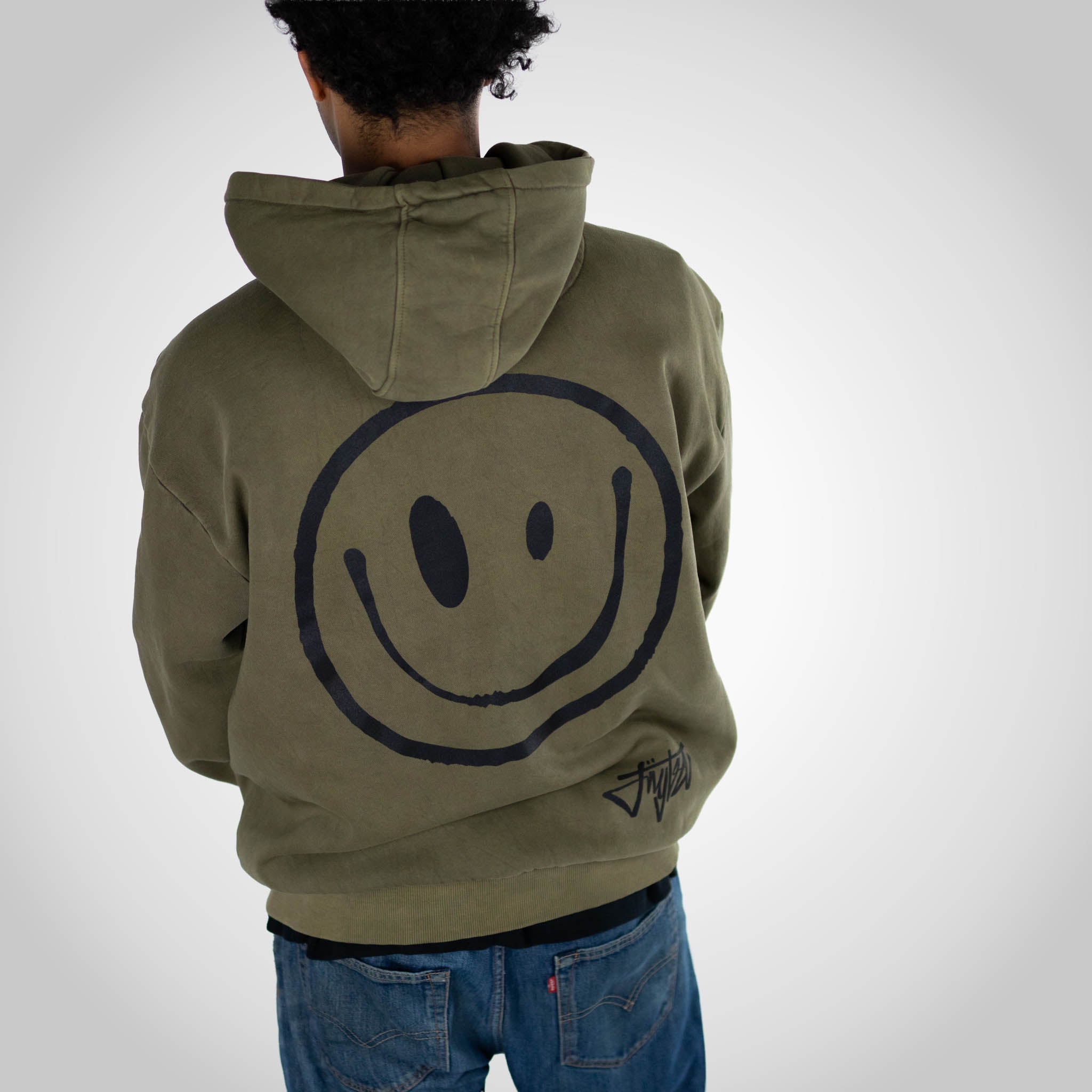 Rewired Smiley Olive Zip Hoody worn in studio with jeans