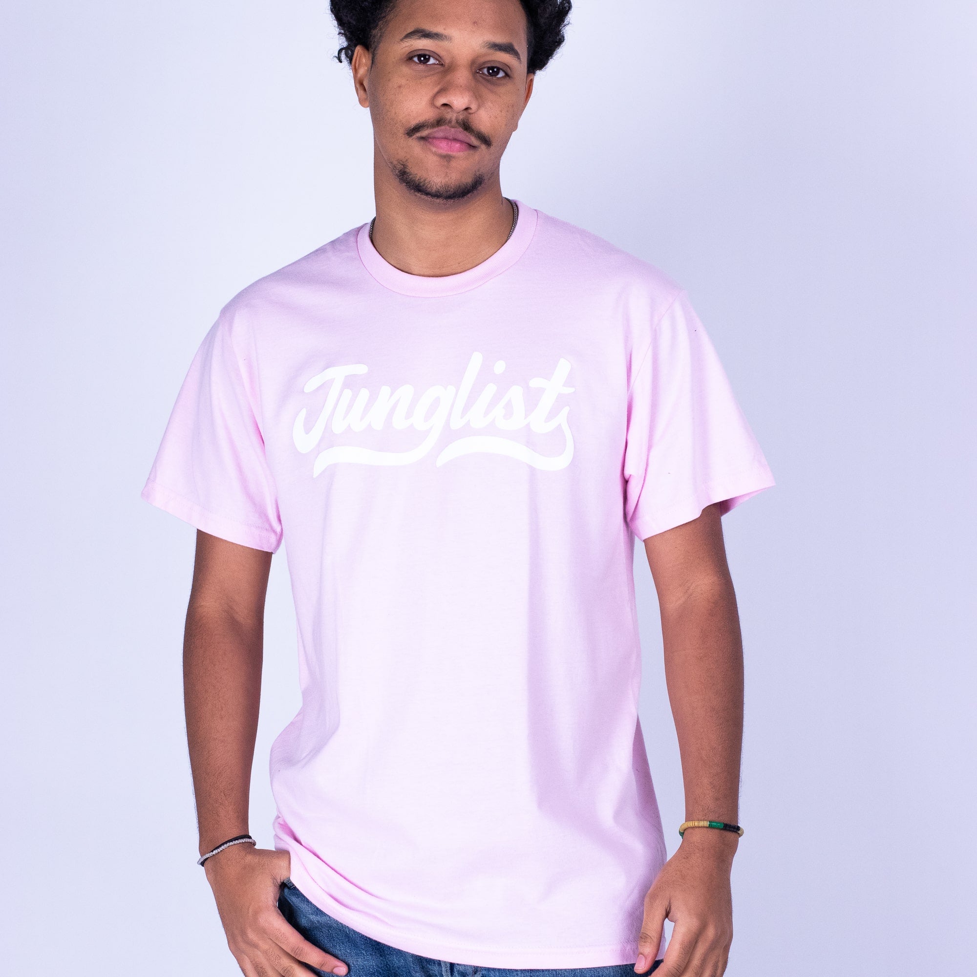 Person wearing a light pink t-shirt with 'Junglelist' text on a plain background