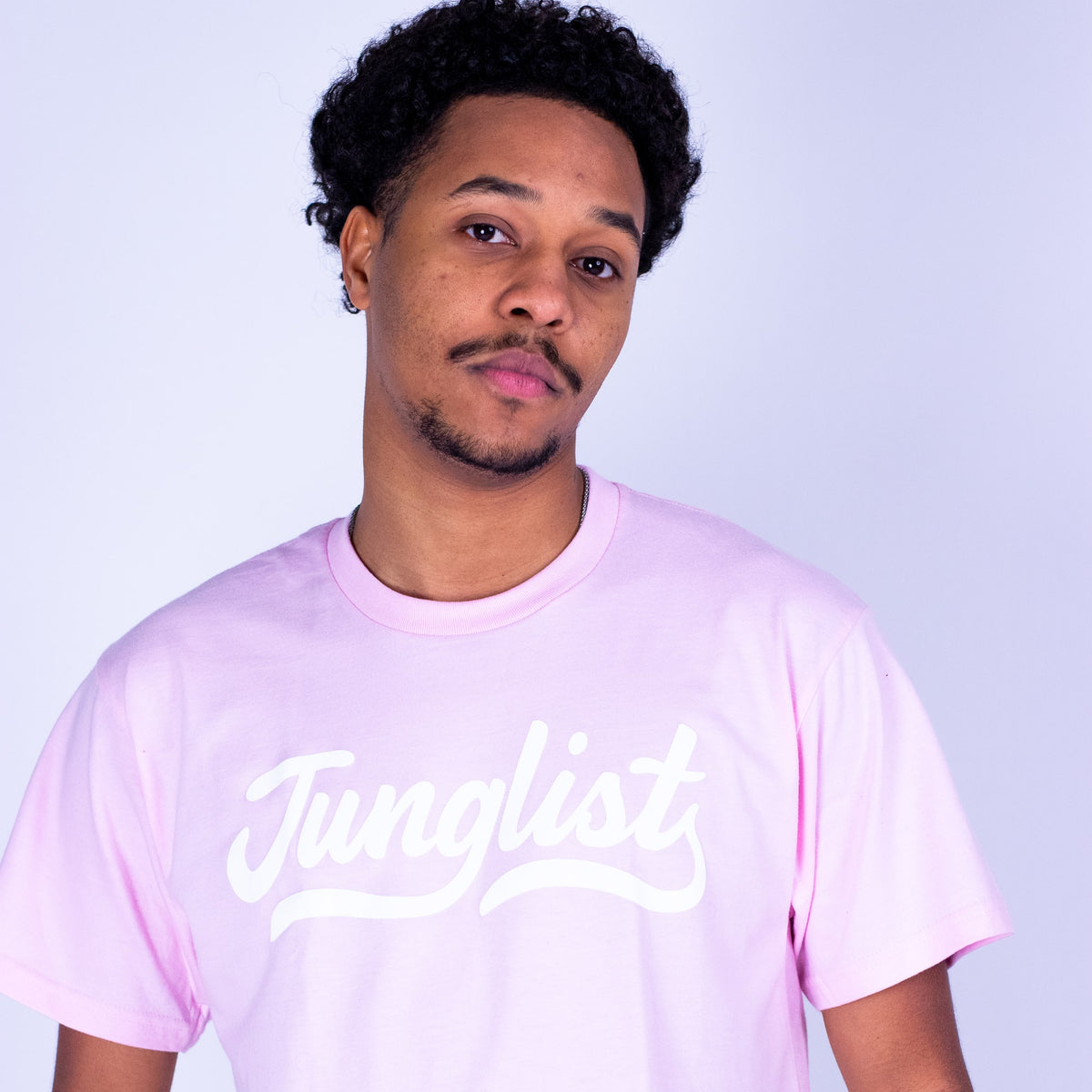 Person wearing a pink t-shirt with 'Junglist' text on a light gray background