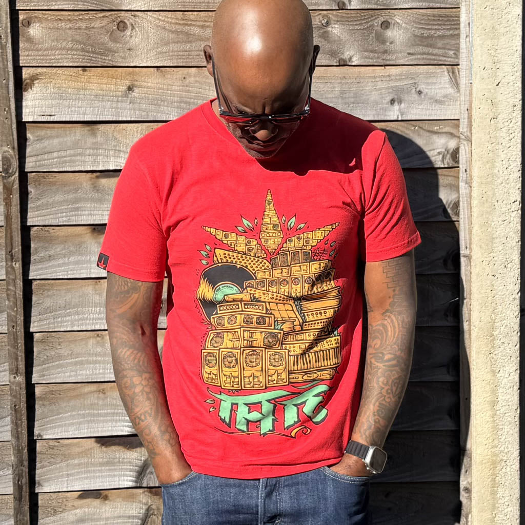 Rodney P wearing a red t-shirt with a graphic design against a wooden wall.