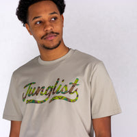 Person wearing a beige t-shirt with 'Junglists' printed on it against a white background