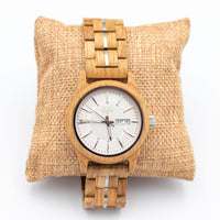 Wooden Junglist wristwatch with a white face on a woven pillow against a white background