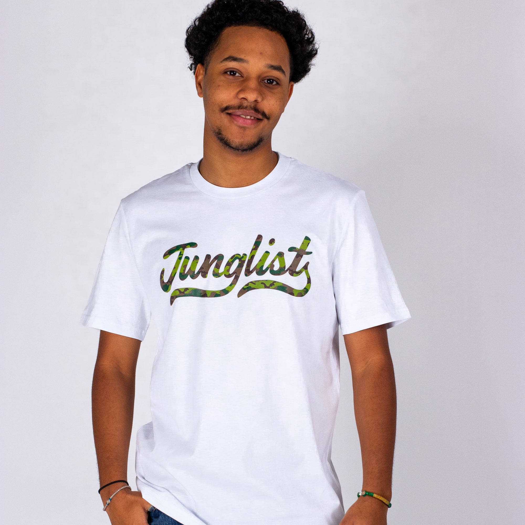 Person wearing a white t-shirt with 'Junglist' printed on it against a plain background
