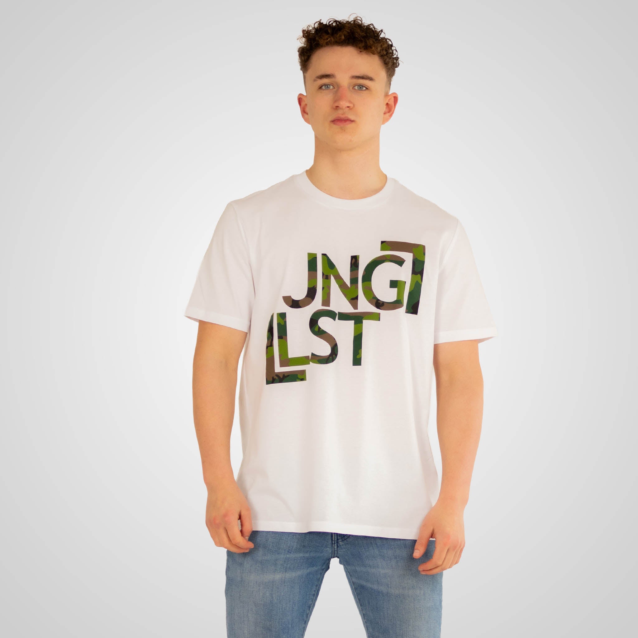 Person wearing a white t-shirt with 'JNGLST' printed on it against a plain background