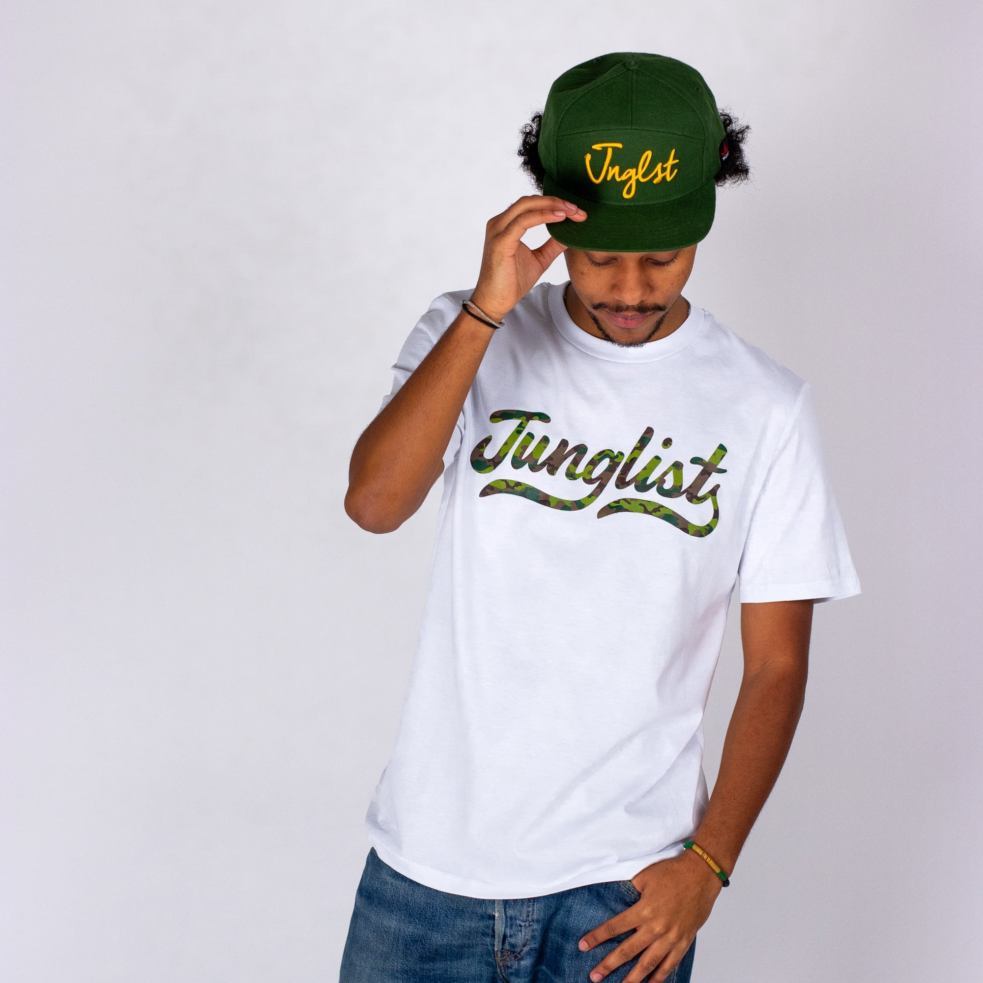 Person wearing a white t-shirt and green cap with 'Junglist' text on a plain background