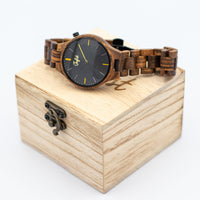 Wooden Junglist watch with black face and yellow accents on a wooden box