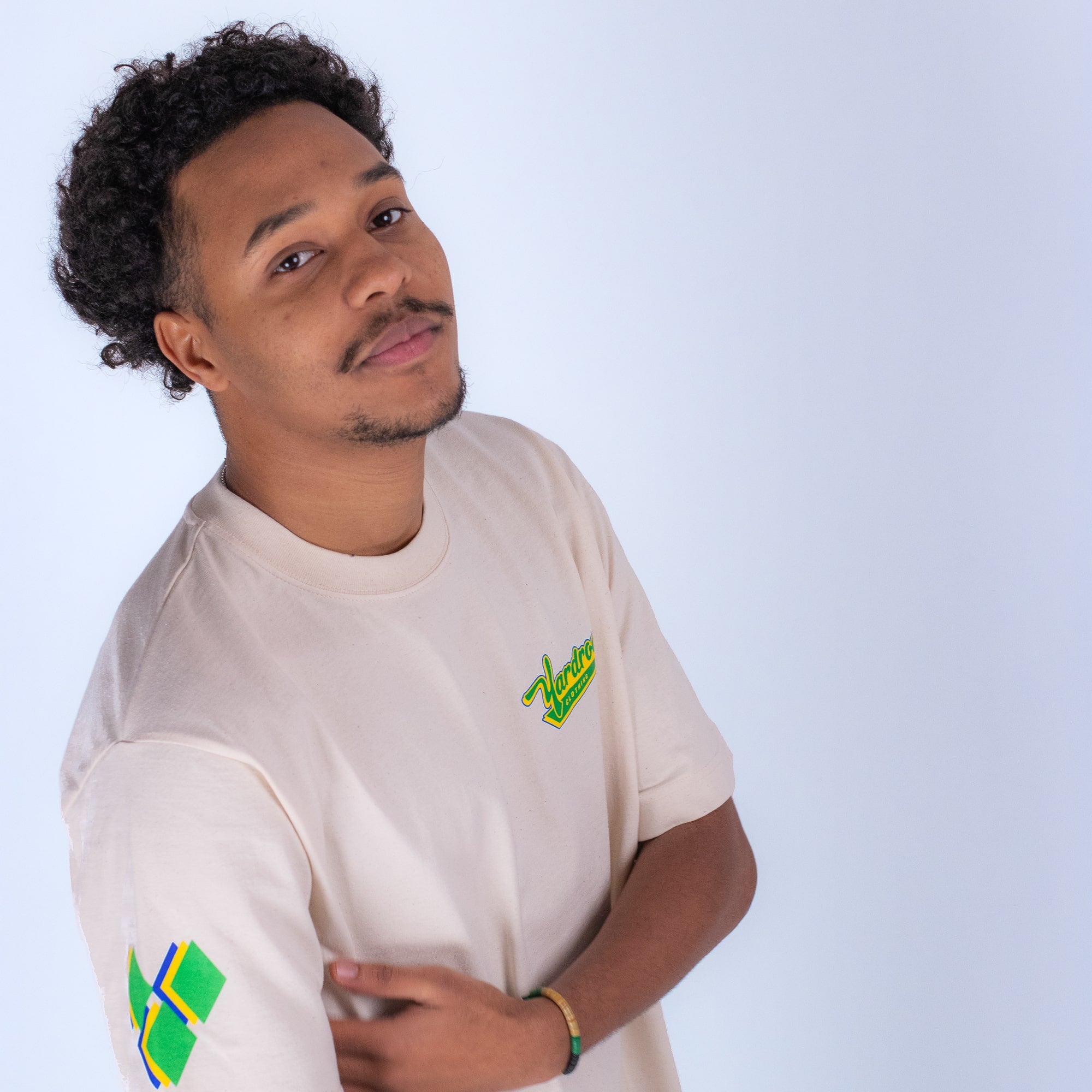 Man wearing a beige t-shirt with a logo on a white background